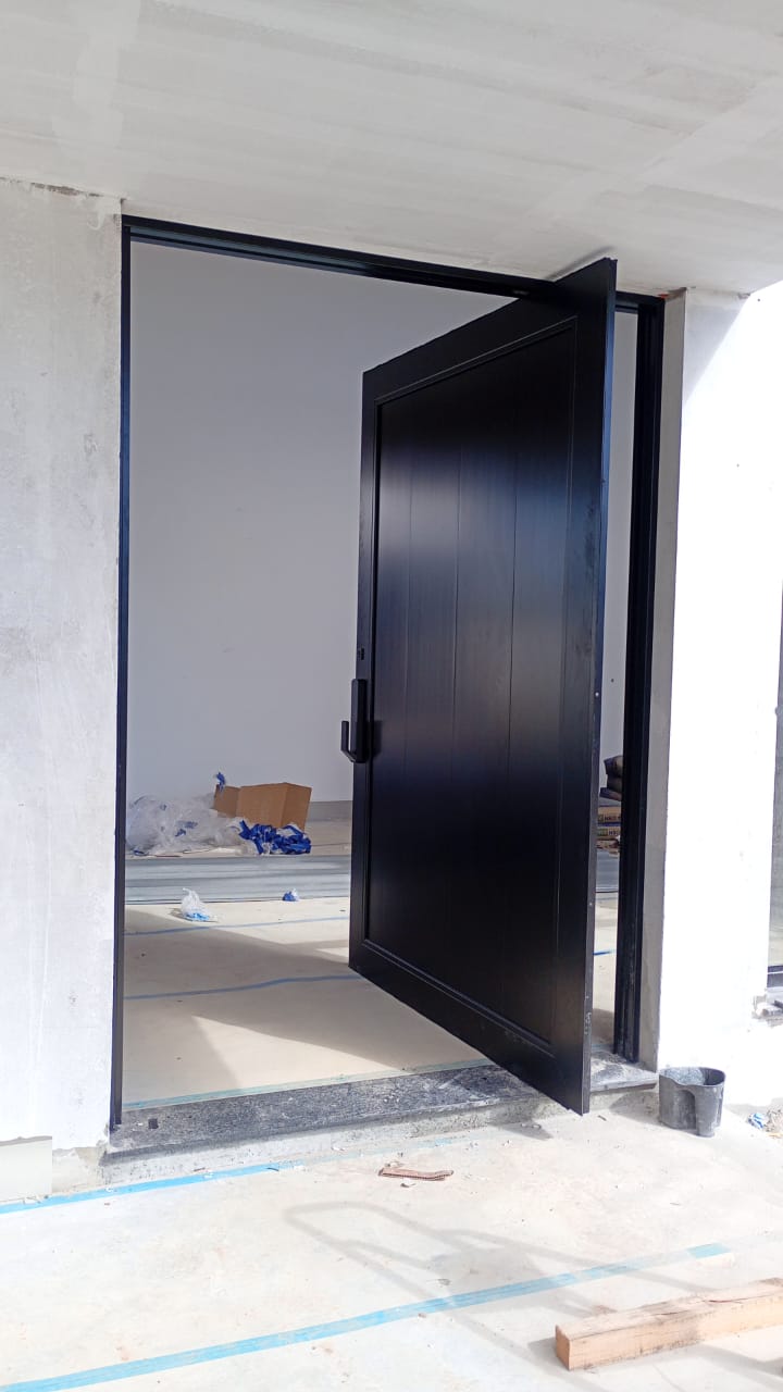 Porta pivotante preta instalada em obra