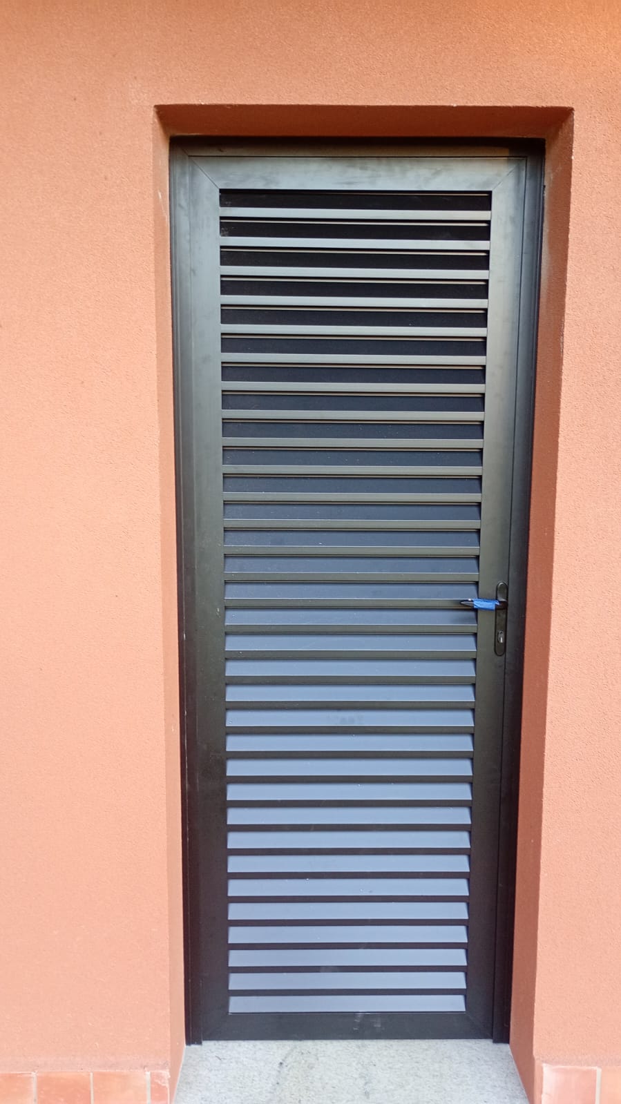 Porta veneziana preta em parede terracota